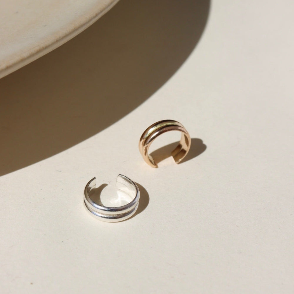 A 14k gold fill + sterling silver doubled layered ear cuff, displayed on a cream backdrop in the sunlight 