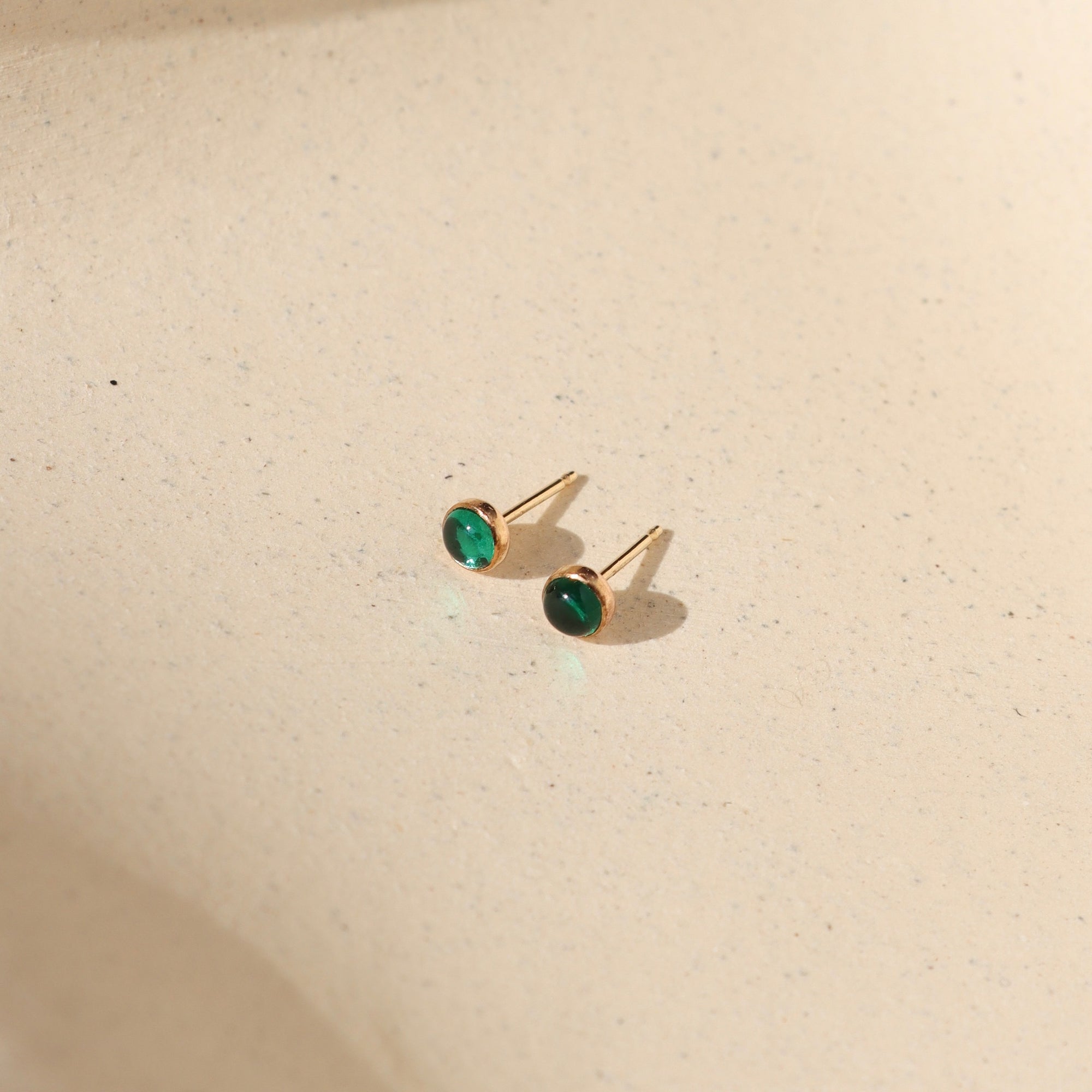 14k gold fill bezel studs with 4mm emerald stones on a light background
