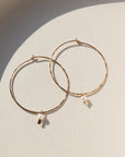 14k gold fill Emma pearl hoops laid on a ceramic plate in the sunlight