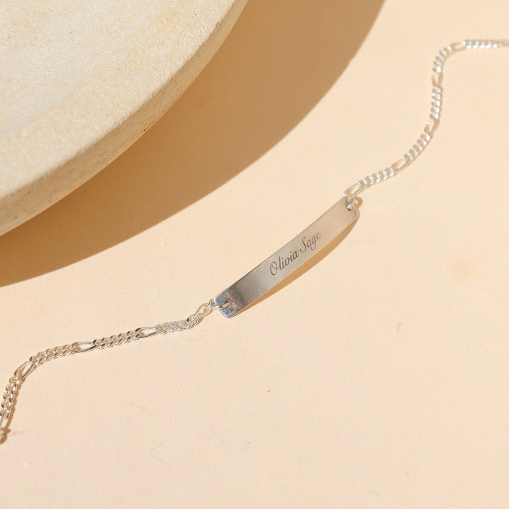 sterling silver chain and bar bracelet with custom engraving on bar on a light dish
