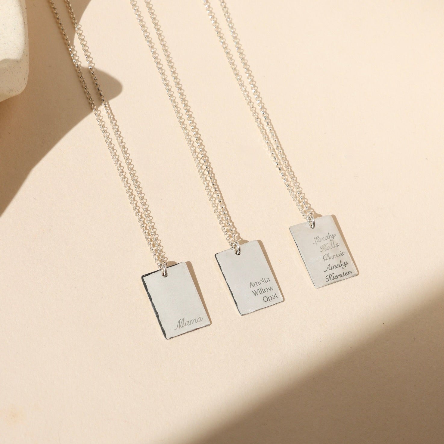 sterling silver engraved pendants on chain necklaces on a light dish