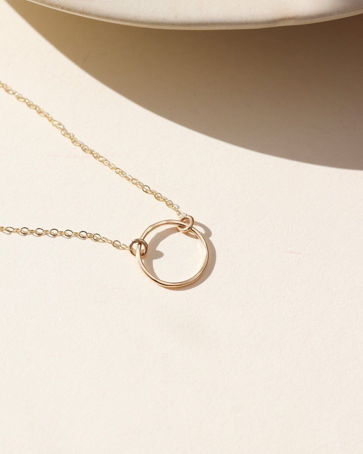 14k Gold fill hammered pendant on a delicate chain necklace in the sunlight