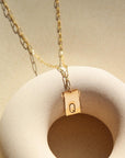 14k gold fill Everly Monogram Necklace on a tan plate in the sunlight