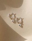 sterling silver heart hoop charms on classic sterling silver hoops laid in the sun