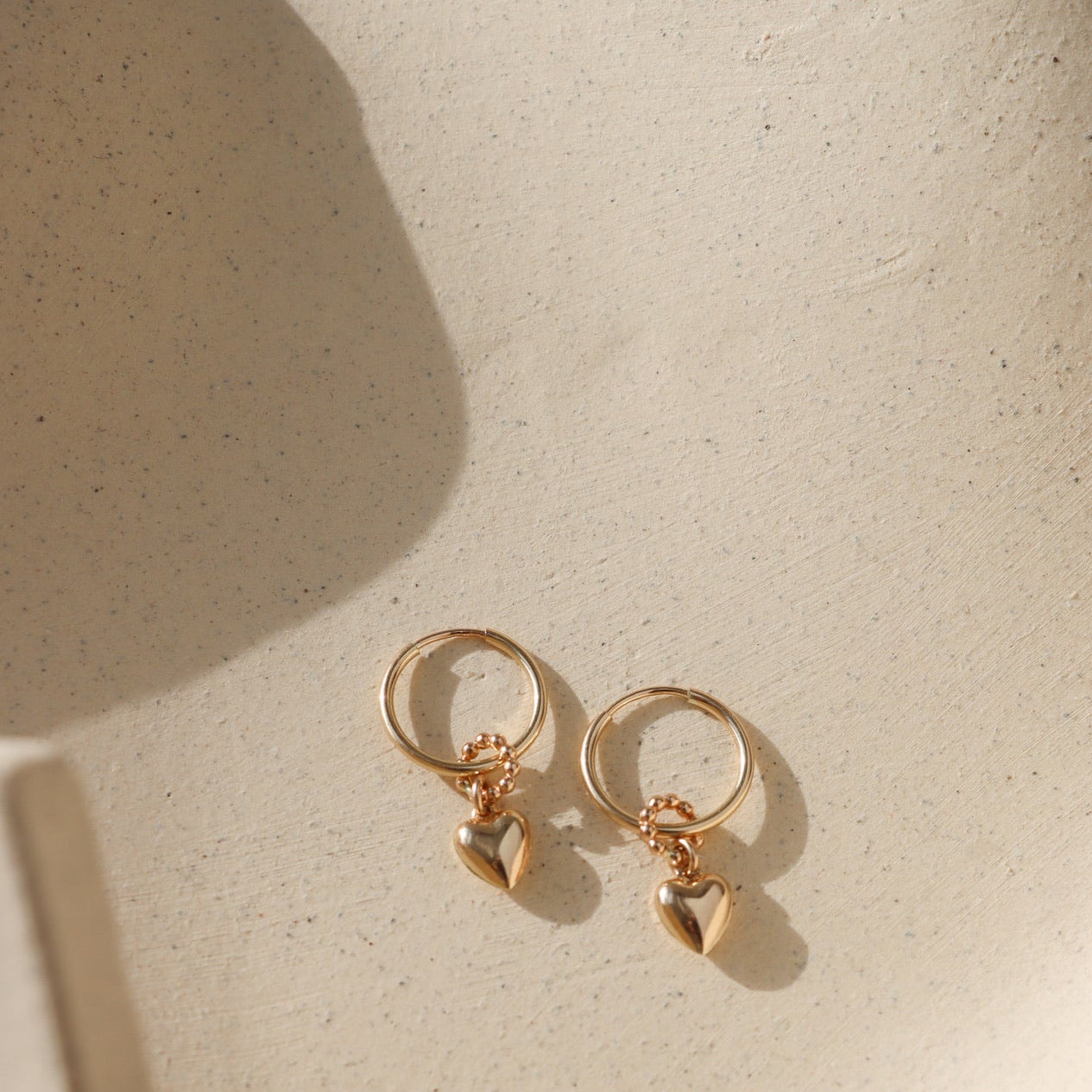 14k gold fill heart charm on simple hoop earring in sunlight