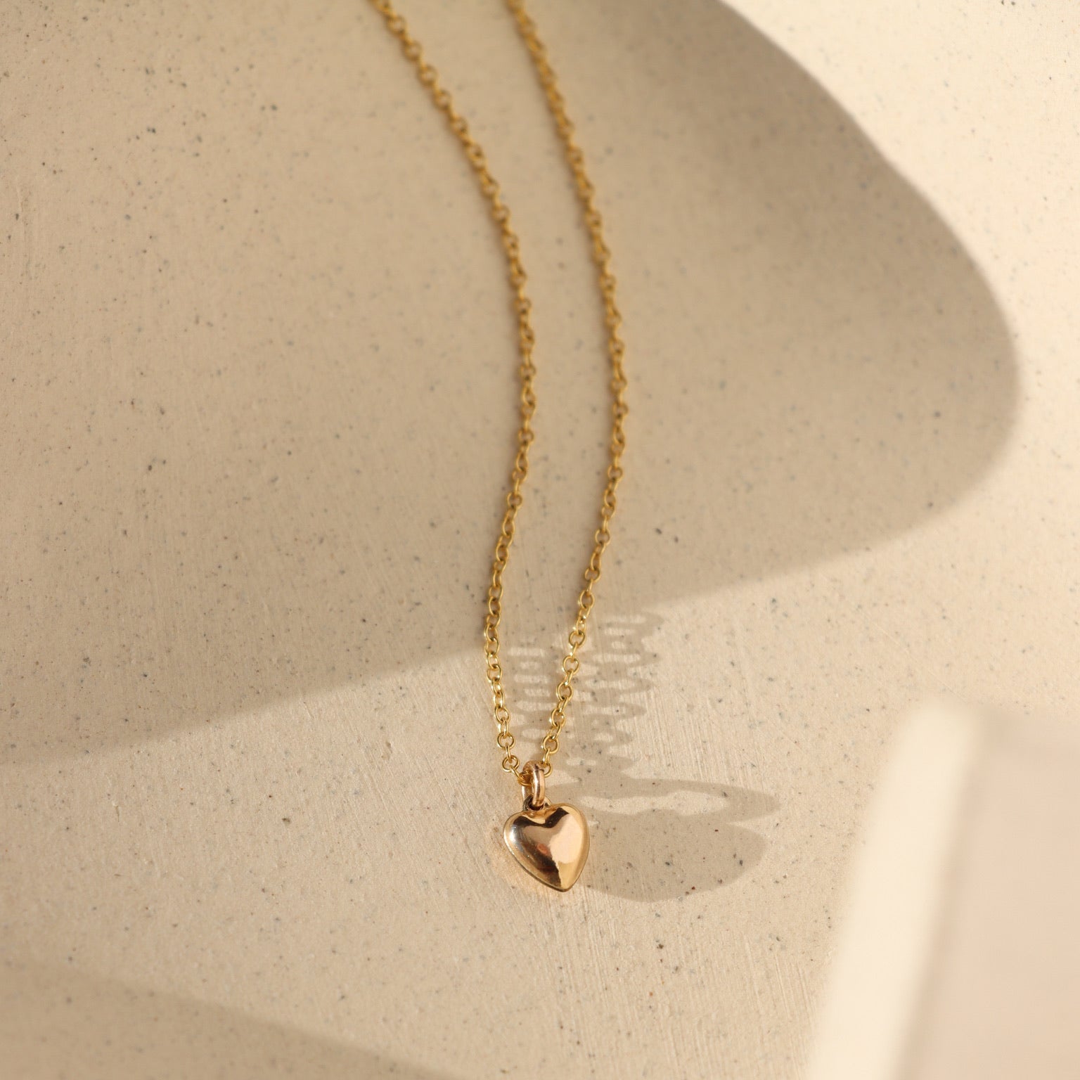 14k gold fill dainty chain with puff heart charm on a light dish