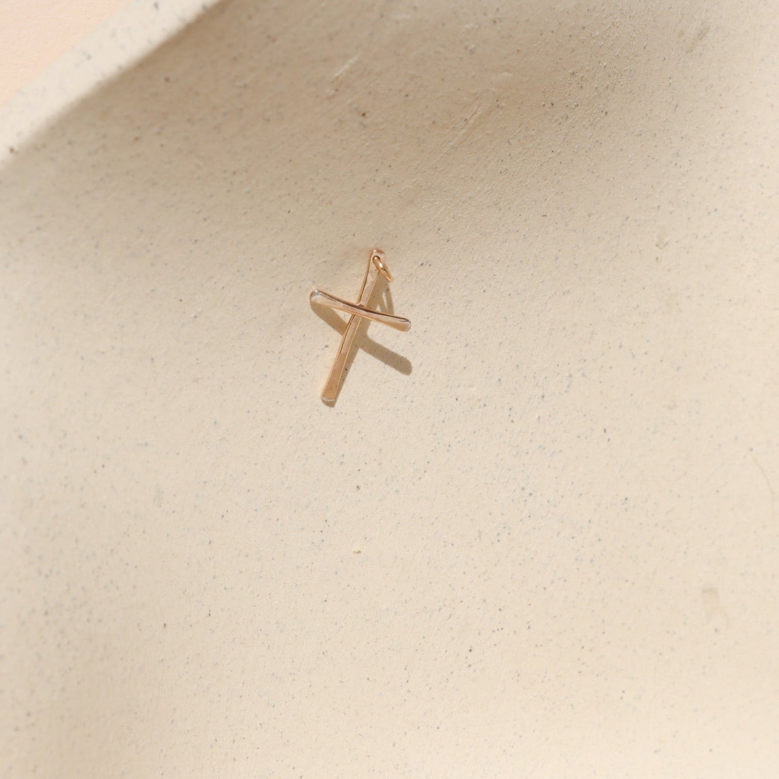 14k gold fill handmade hammered cross charm on a light background
