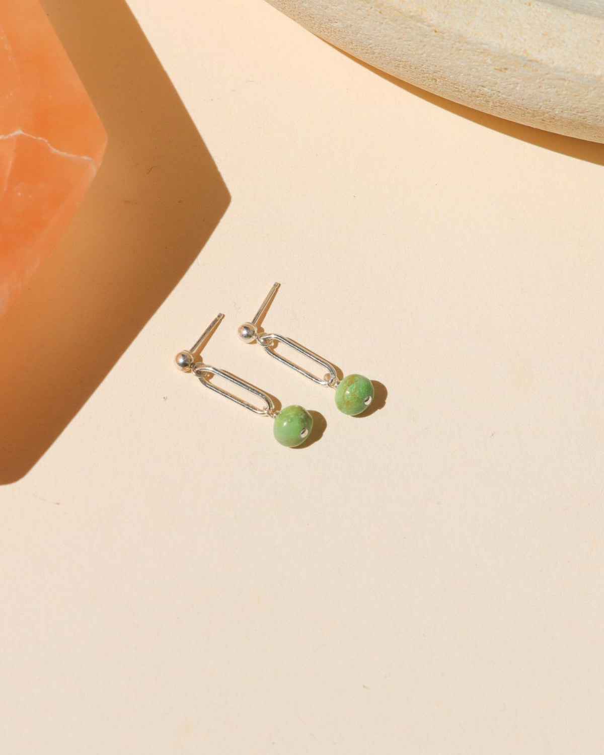 sterling silver stud earrings with turquoise bead drops on a light dish