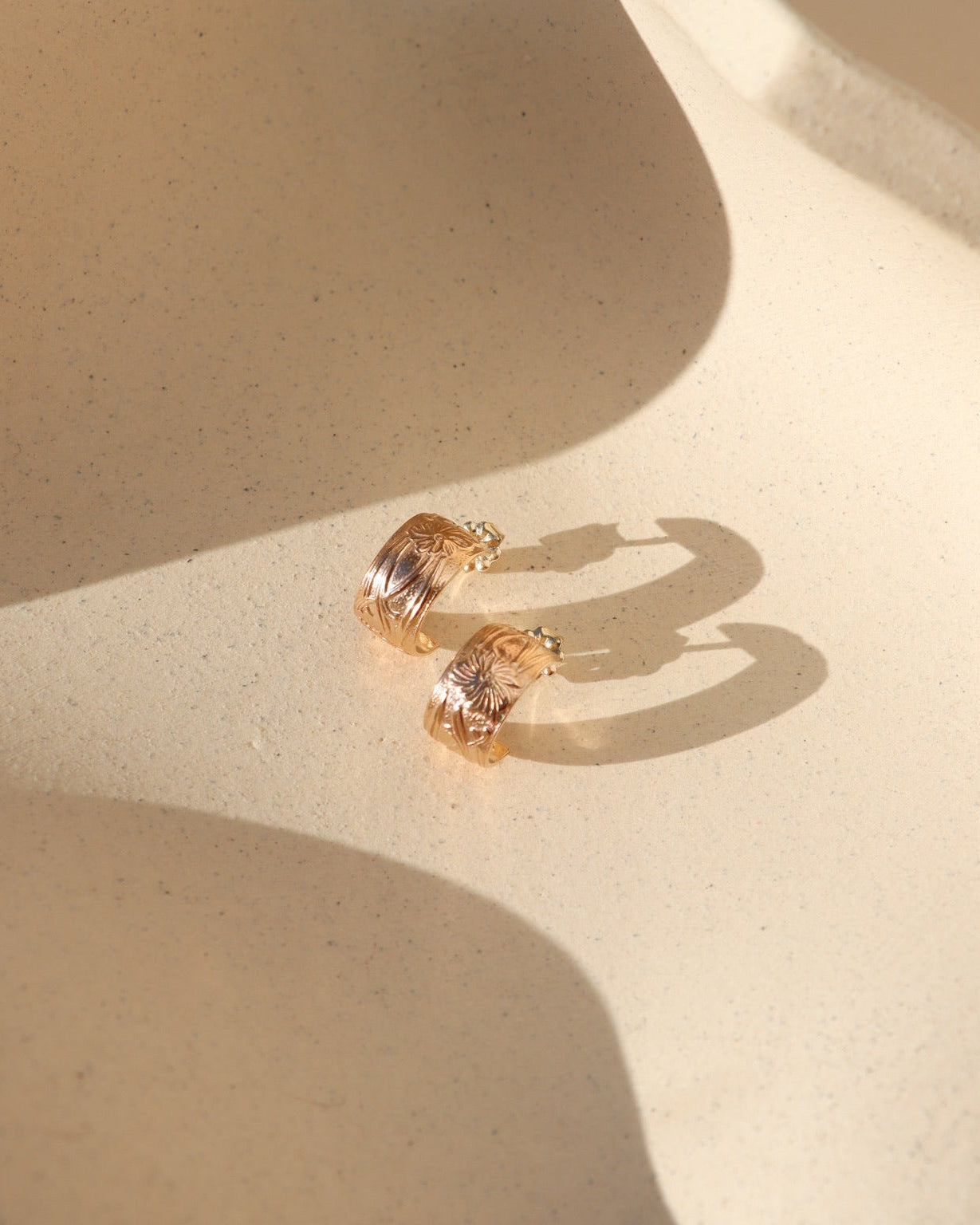 Close-up of Florence gold fill huggie  earrings featuring a floral design