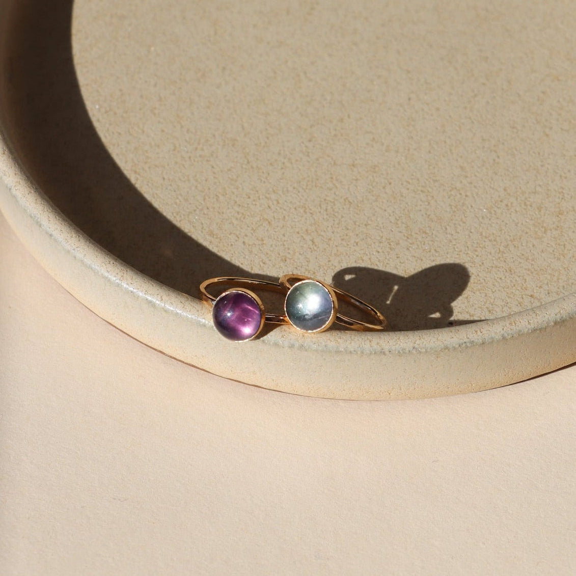 2 14k gold fill rings with round fluorite stones on a light dish