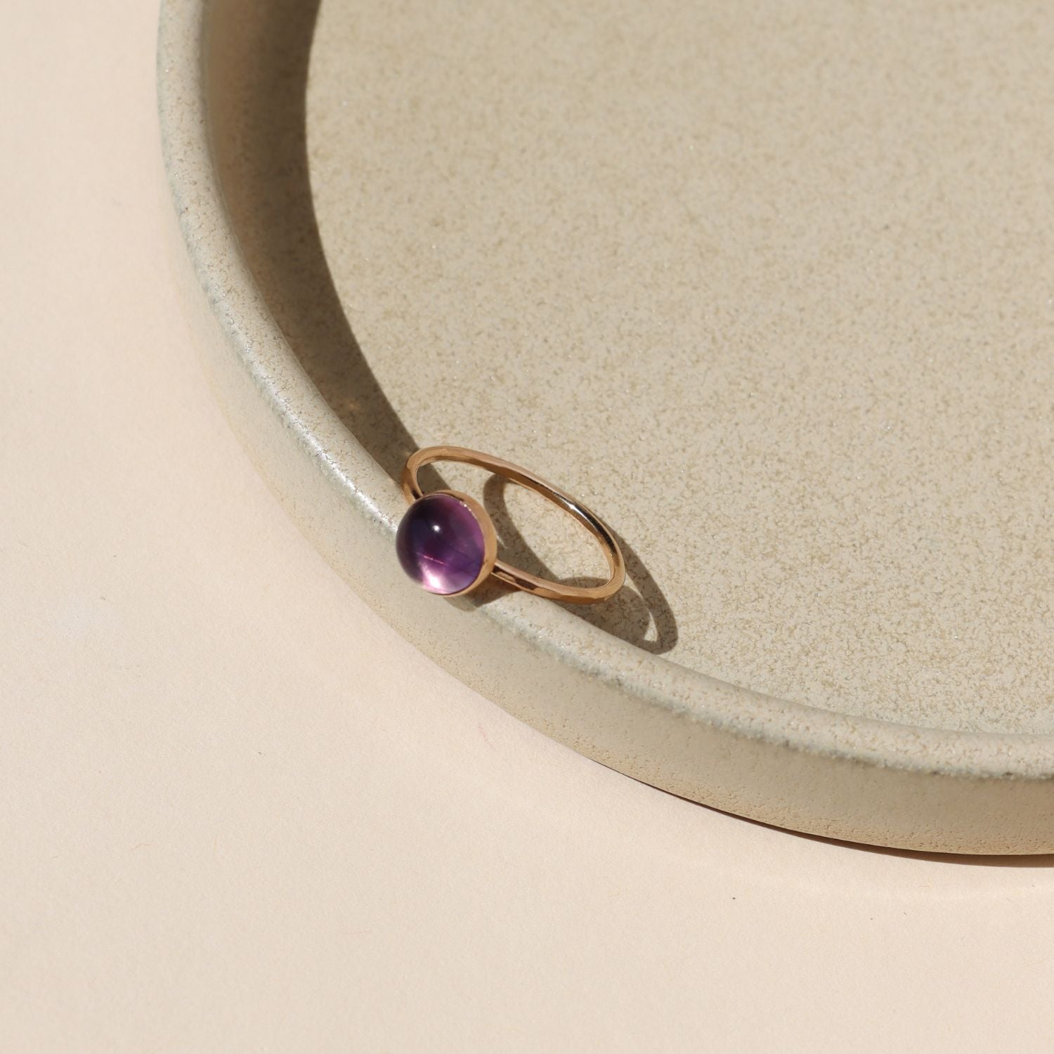 14k gold fill ring with round fluorite stone on a light dish