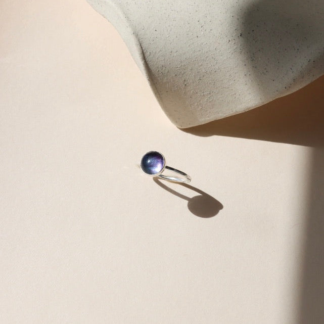 sterling silver ring setting with round fluorite stone on a light background
