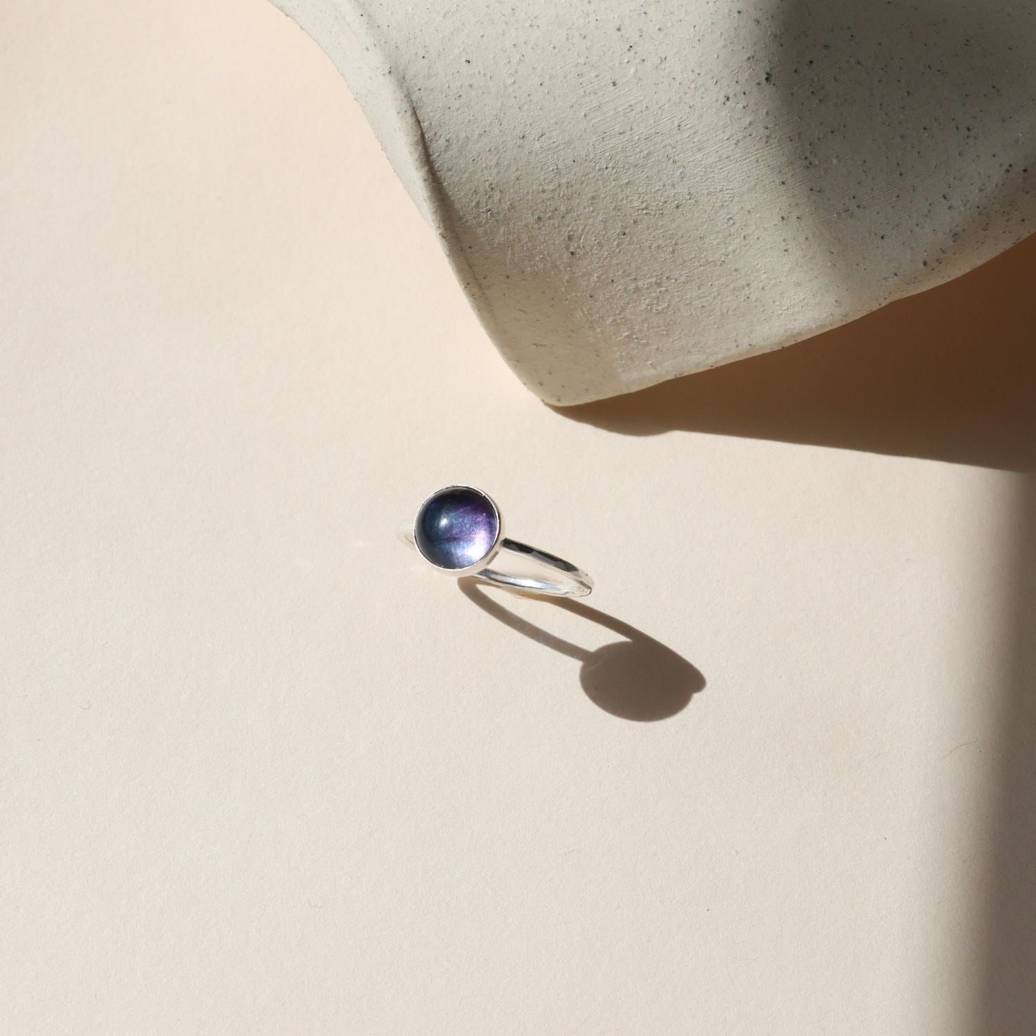 sterling silver ring with round fluorite stone on a light dish