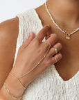Model wearing 14k gold fill hand chain with pearls paired with other 14k gold fill jewelry