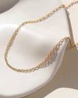 14k gold filled gemma chain laid on a white ceramic dish in the sun.