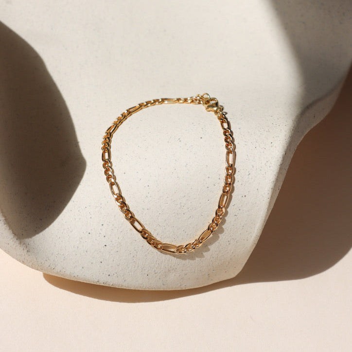 14k gold fill figaro chain bracelet on a light dish