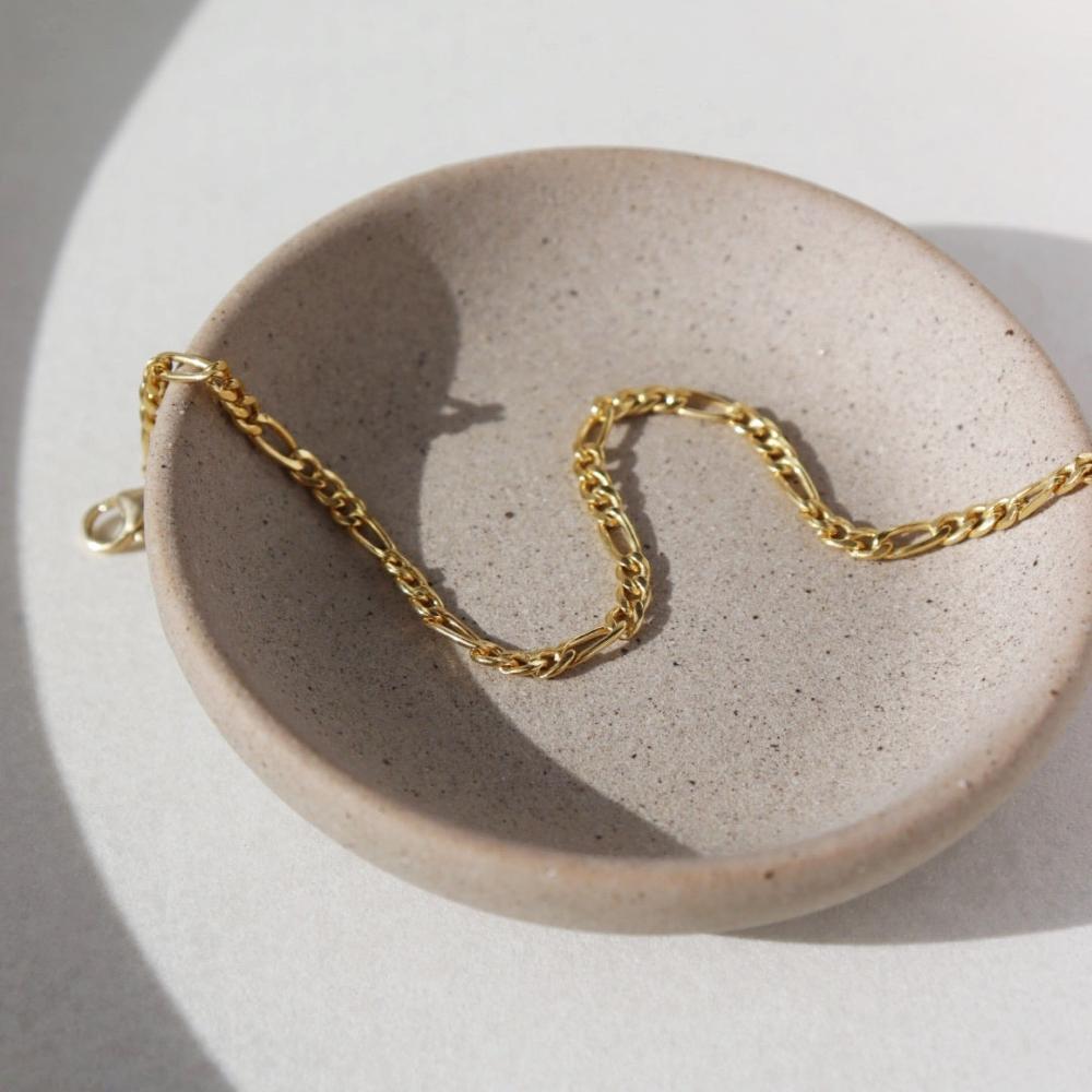 14k gold fill figaro chain bracelet on a light dish
