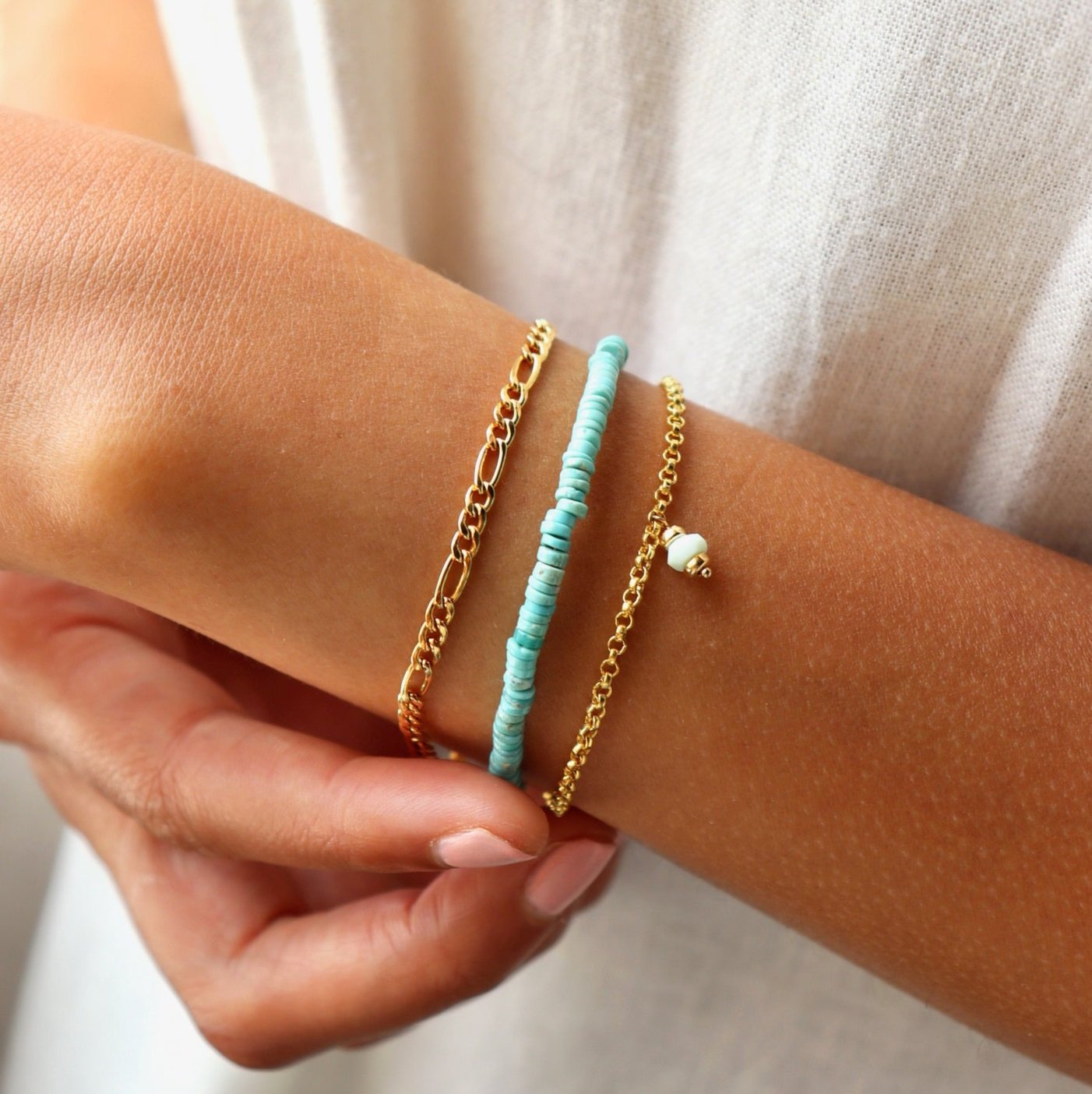 model wearing 14k gold fill chain figaro chain bracelet paired with a beaded bracelet and a rolo chain bracelet