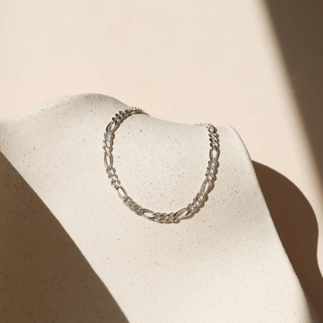 sterling silver figaro chain bracelet on a light dish