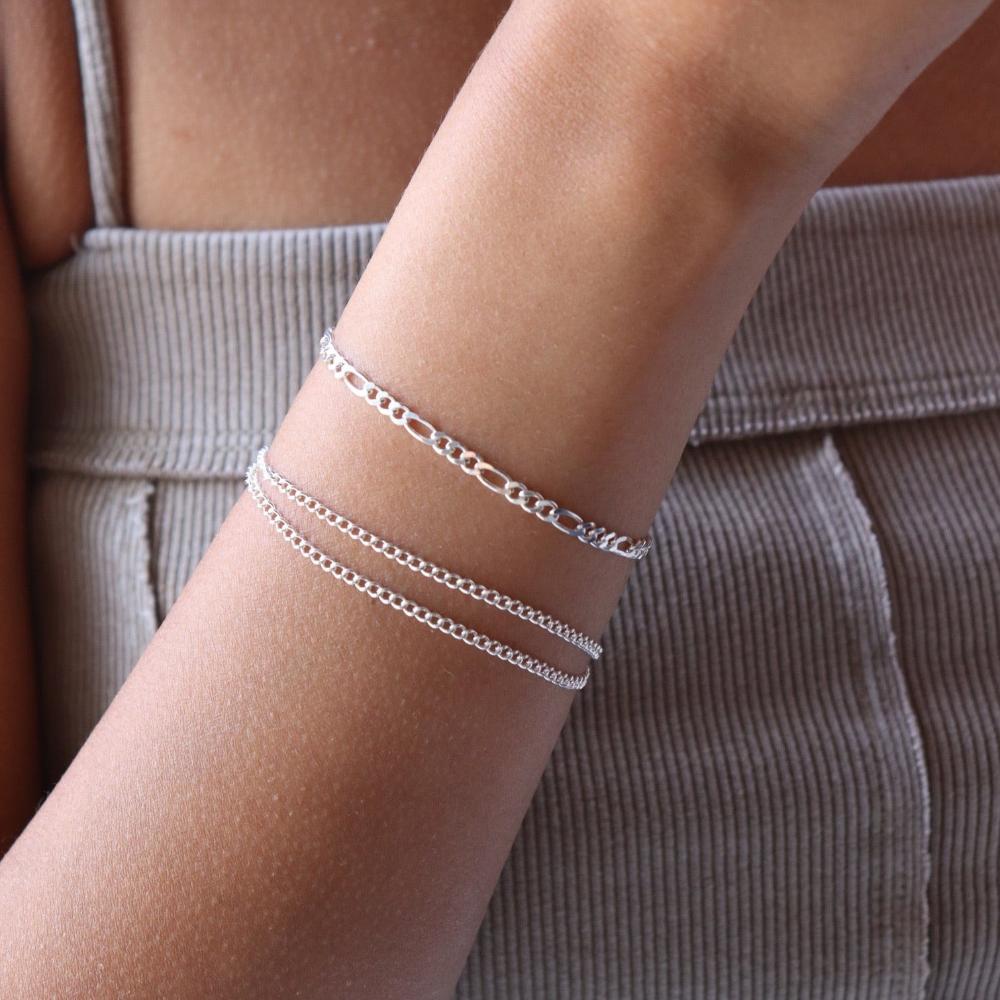 model wearing sterling silver figaro chain bracelet with 2 delicate curb chain bracelets