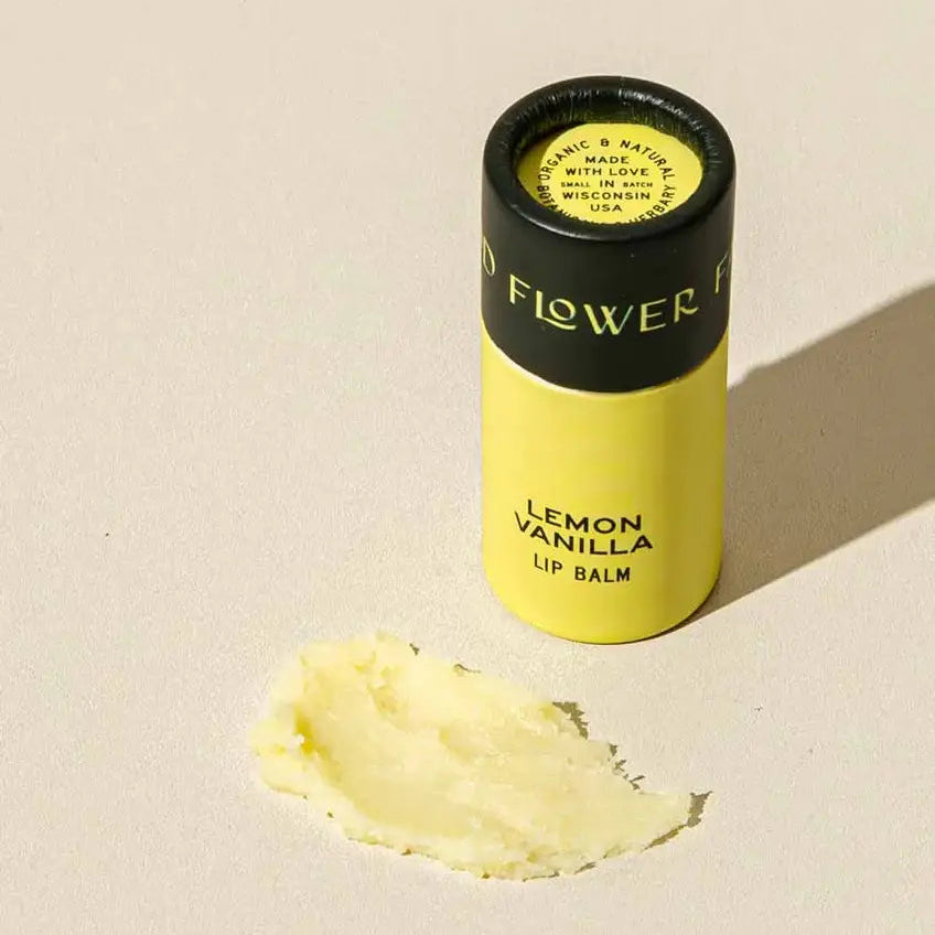 Lemon Vanilla lip balm with a visible brand name on a beige background