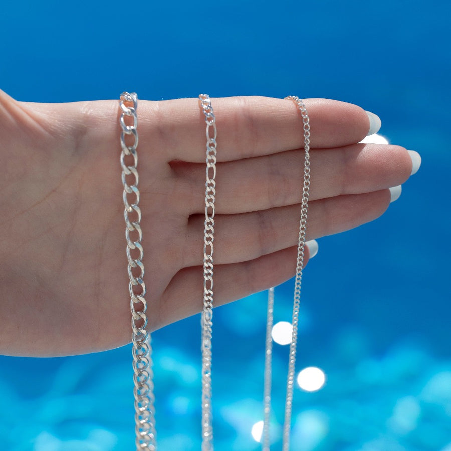 925 sterling silver La mer necklace, Gigi necklace, and Alex chain laid on a hand in the sunlight.