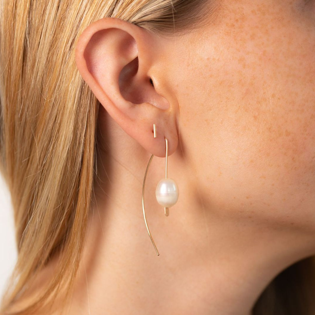 Delicate sterling silver half-moon earrings with smooth freshwater pearls set beneath a curved crescent design.