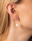 Delicate sterling silver half-moon earrings with smooth freshwater pearls set beneath a curved crescent design.