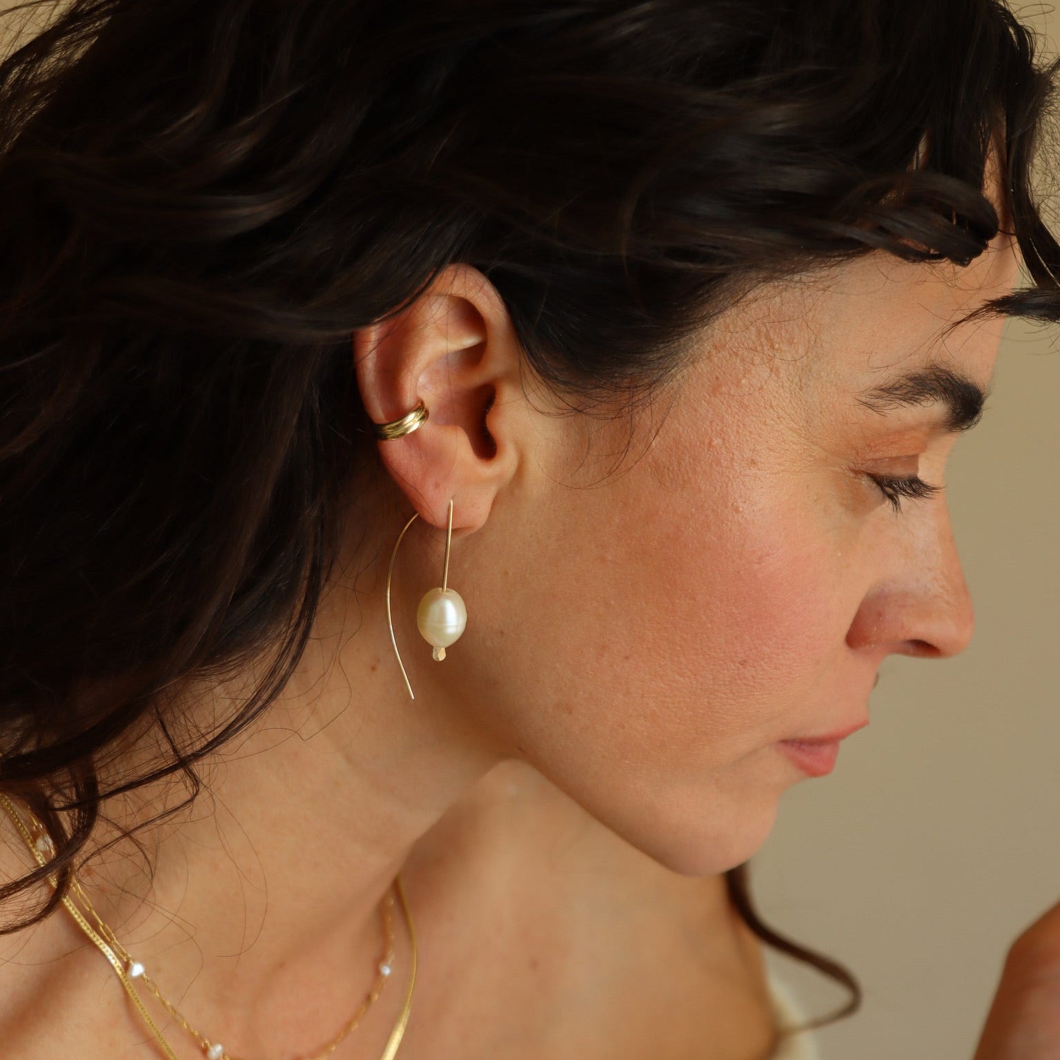 Delicate sterling silver half-moon earrings with smooth freshwater pearls set beneath a curved crescent design.