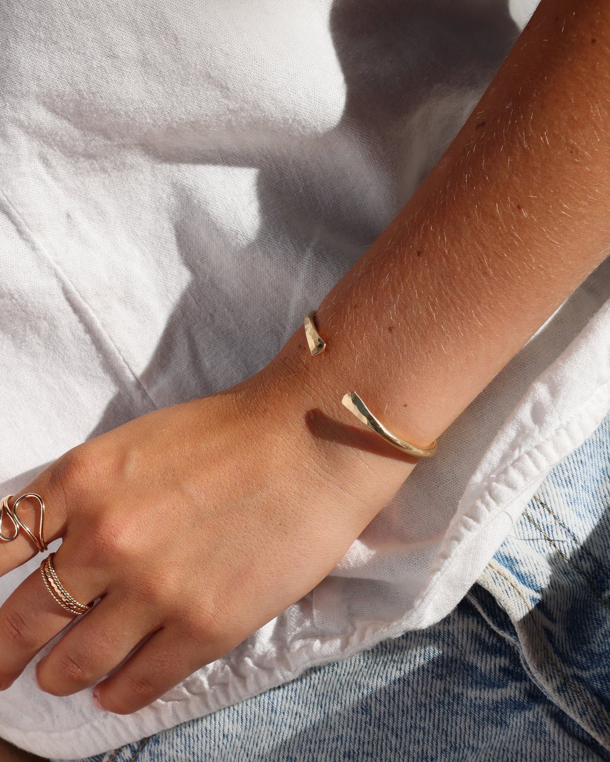 model wearing 14k gold fill hammered cuff bracelet with 14k gold fill rings 