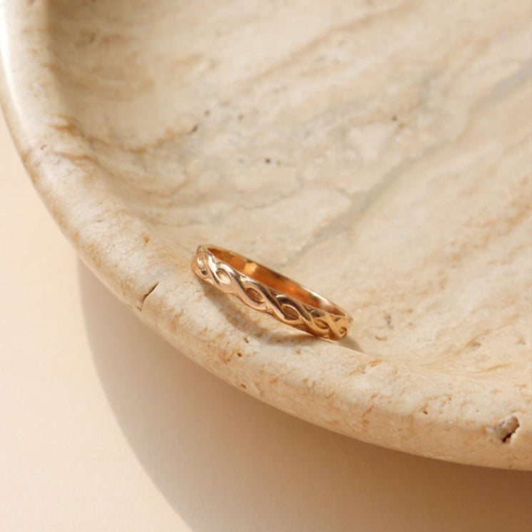 14k gold fill braided textured ring, displayed on a marble back drop 