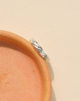 Sterling Silver braided textured ring, displayed on a orange dish