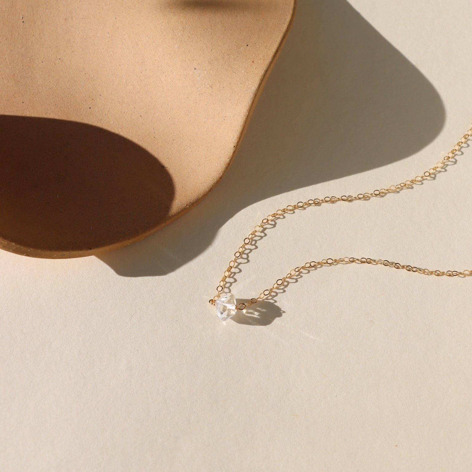 Herkimer diamond pendant necklace featuring a raw, double-terminated quartz crystal on a delicate gold chain.