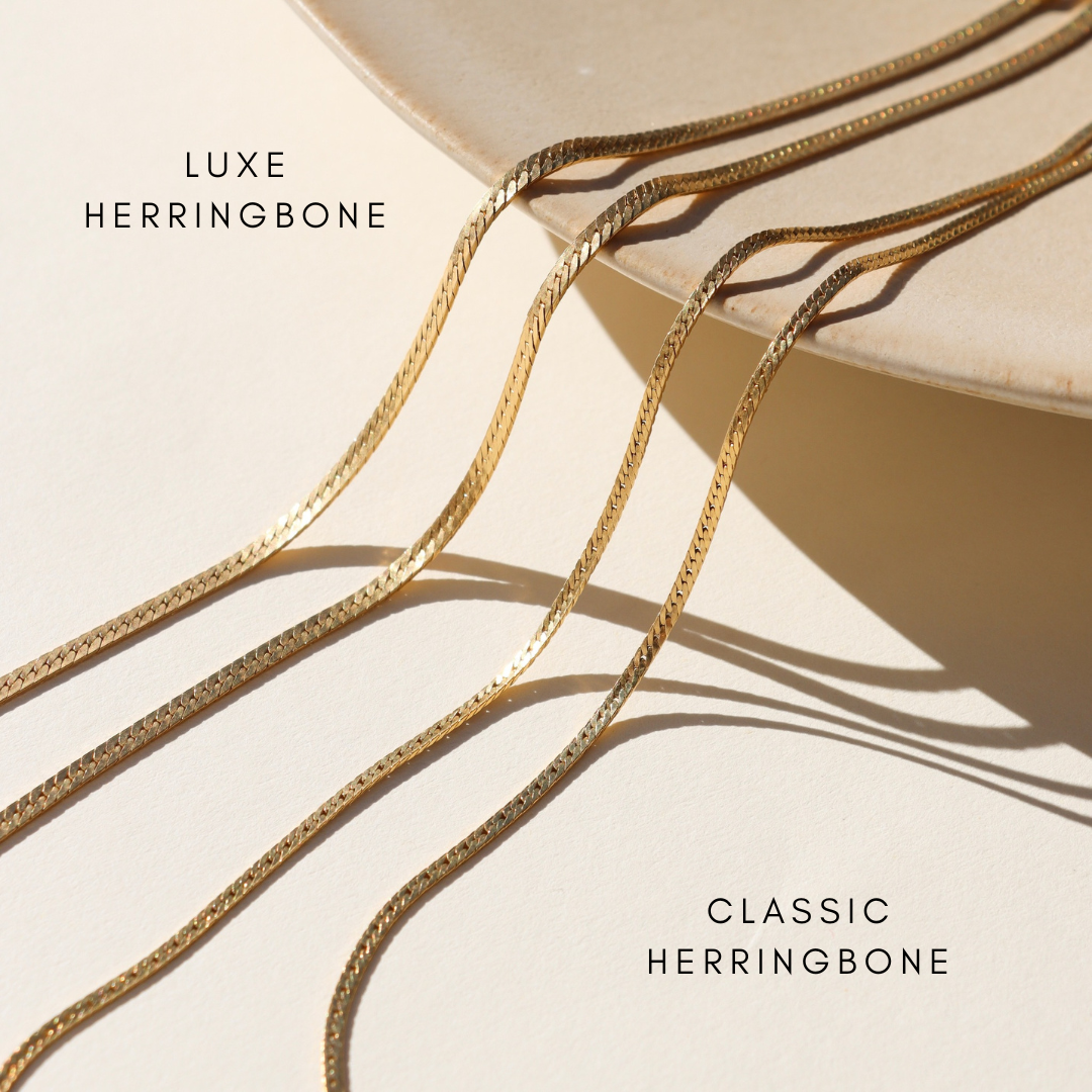 2 14k gold fill herringbone chain necklaces on a dish 