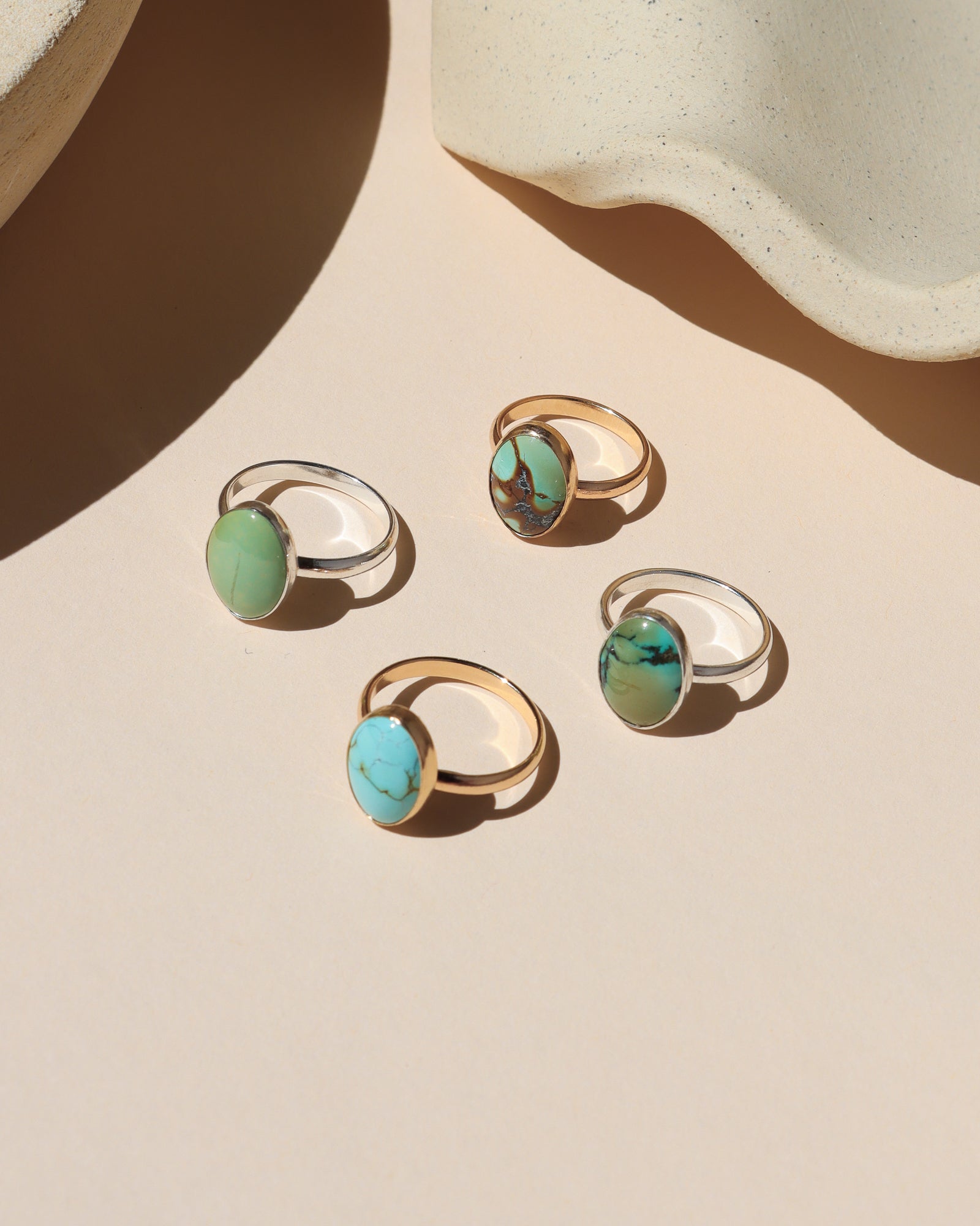 sterling silver and 14k gold fill rings with oval turquoise gemstones in the sunlight