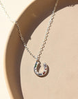 sterling silver dainty chain with horseshoe charm on a light dish