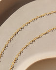 14k gold fill delicate chain, photographed on a cream colored ceramic dish