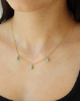 A simple 14k gold fill chain adorned with three charms of stacked turquoise stones, photographed on a model