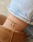 14k gold fill anklet with a swivel push-gate clasp holding a seashell charm and a turquoise charm, photographed on a model wearing brown ugg boots and light wash jeans