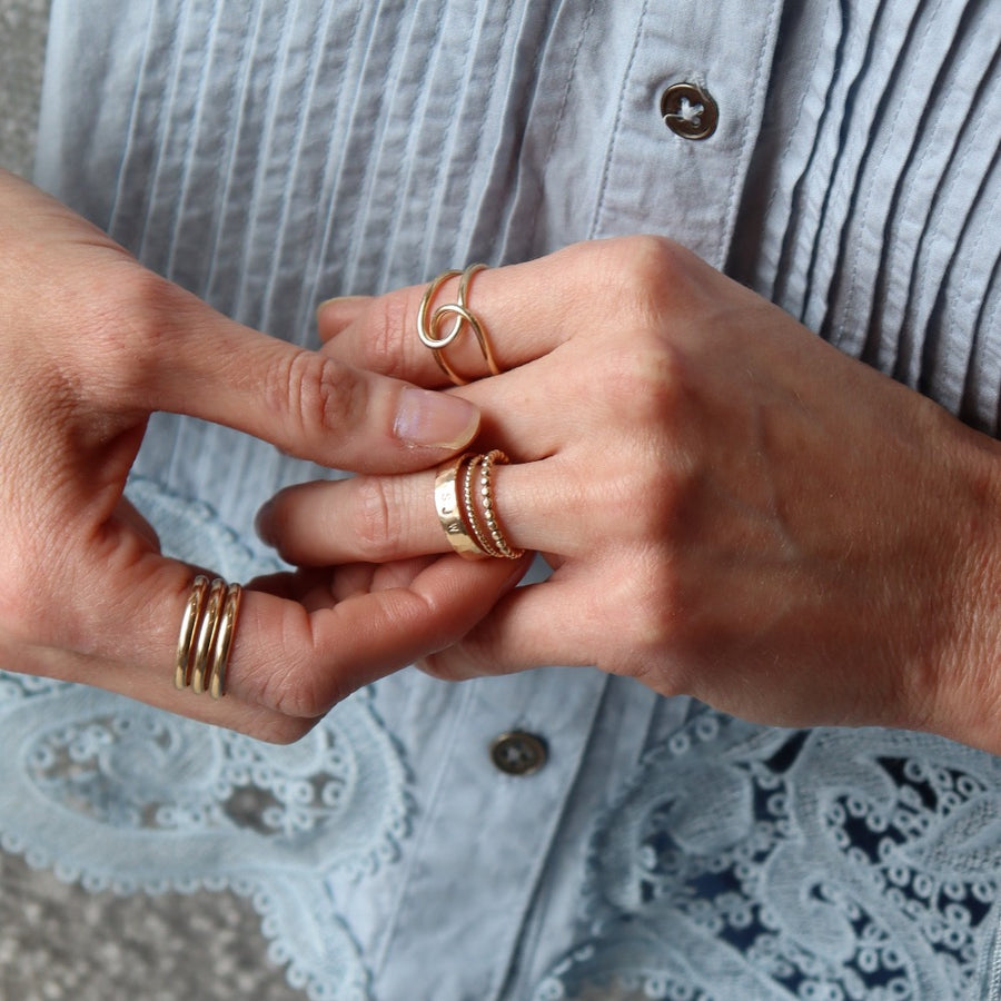 Model wearing 14k gold fill initial stamped ring in the sunlight. This ring features a hammered band that you get to customize with name or initials of your choice.