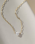 mother of pearl heart charm on Cosette chain, photographed on a sunlit tabletop