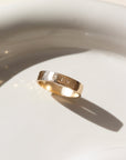 14k gold fill Initial stamped ring laid on a white plate in the sunlight. This ring features a hammered band that you get to customize with name or initials of your choice.