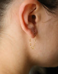 a heart chain on stud earrings, photographed on a model