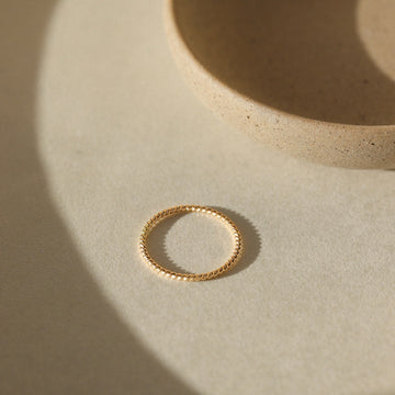 14k gold fill Spiral Ring placed on a white paper in the sunlight. This ring features a simple spiral band making it perfect for stacking.