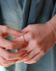 a young girl putting on a 925 sterling silver spiral band with a tiny heart charm, and a heart chain bracelet