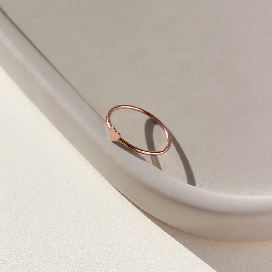 14k rose gold fill heart ring. This ring features a smooth band with a tiny heart. This ring is so cute stacked with any of the stacking rings at Token Jewelry.