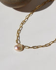 14k gold fill Anklet featuring a freshwater pearl, laid on a white paper in the sunlight.