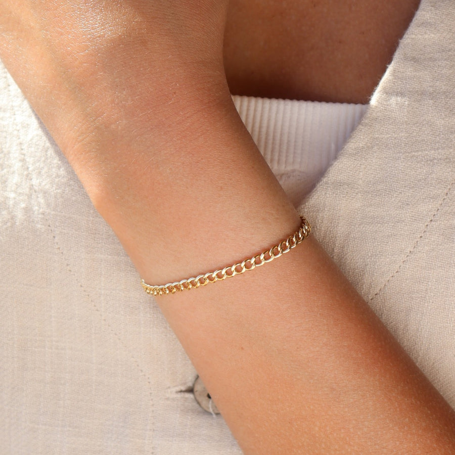 a woman's wrist wearing Token Jewelry's Demi Alexandra Bracelet, a bold link chain. She's also wearing a cream vest with buttons