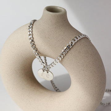 925 sterling silver Modern Muse Initial Necklace in Sterling Silver laid on a tan pot. This necklace feature the Carter chain with the choice of adding on an initial charm.
