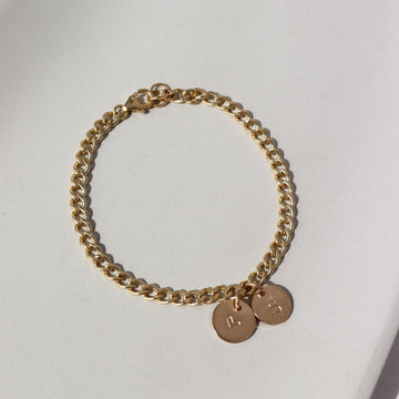 14k gold fill bold link chain Demi Alexandra Bracelet featuring two gold fill disks with a heart and an "S", photographed on a white tabletop